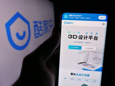 Stuttgart, Almanya - 08-24-2024: Çinli çevrimiçi bilgi şirketi Kujiale 'in internet sayfası ile iş logosu önünde cep telefonu tutan kişi. Telefon ekranının merkezine odaklan.