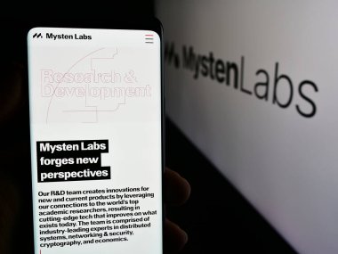 Stuttgart, Almanya - 08-24-2024: Web3 altyapı şirketi Mysten Lab. 'ın web sayfası ile logo önünde cep telefonu tutan kişi. Telefon ekranının merkezine odaklan.