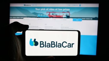 Stuttgart, Almanya - 08-24-2024: Fransız carpooling şirketi BlaBlaCar 'ın (Comuto SA) logosuna sahip cep telefonu sahibi kişi iş sayfası önünde. Telefon ekranına odaklan.