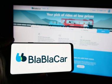 Stuttgart, Almanya - 08-24-2024: Web sitesi önünde üzerinde Fransız carpooling şirketi BlaBlaCar 'ın (Comuto SA) logosu bulunan akıllı telefon sahibi kişi. Telefon ekranına odaklan.