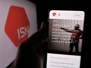 Stuttgart, Almanya - 08-25-2024: ABD 'li sözleşmeli yazılım ISN Software Corporation' ın web sayfası ile logo önünde akıllı telefon tutan kişi. Telefon ekranının merkezine odaklan.