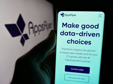 Stuttgart, Almanya - 08-25-2024: ABD 'li mobil pazarlama şirketi AppsFlyer Ltd.' nin web sayfası ile birlikte iş logosu önünde cep telefonu tutan kişi. Telefon ekranının merkezine odaklan.