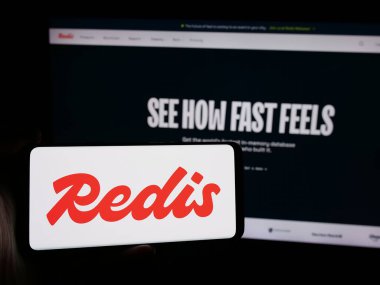 Stuttgart, Almanya - 08-25-2024: ABD 'nin hafıza veritabanı şirketi Redis Inc.' in logosuna sahip akıllı telefon sahibi kişi web sitesinin önünde. Telefon ekranına odaklan.