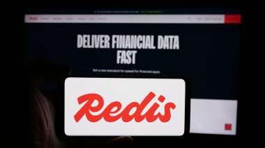 Stuttgart, Almanya - 08-25-2024: ABD 'nin hafıza veritabanı şirketi Redis Inc.' in logosuyla cep telefonu sahibi kişi iş sayfasının önünde. Telefon ekranına odaklan.