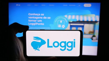 Stuttgart, Almanya - 08-26-2024: Brezilyalı yazılım şirketi Loggi Tecnologia Ltda 'nın logosuna sahip cep telefonu sahibi kişi. İş sayfasının önünde. Telefon ekranına odaklan.