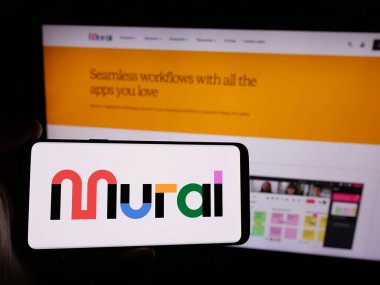 Stuttgart, Almanya - 08-26-2024: İnternet sitesi önünde üzerinde ABD 'li görsel çalışma alanı şirketi Tactios Inc. (MURAL) logosu bulunan kişi. Telefon ekranına odaklan.
