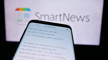 Stuttgart, Almanya - 08-26-2024: Japon haber uygulaması şirketi SmartNews Inc. 'in web sitesi ile ticaret logosu önünde akıllı telefon. Telefon ekranının sol üst kısmına odaklan.