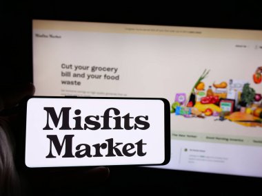 Stuttgart, Almanya - 08-26-2024: İnternet sitesi önünde ABD 'li market dağıtım şirketi Misfits Market Inc.' in logosuna sahip kişi. Telefon ekranına odaklan.