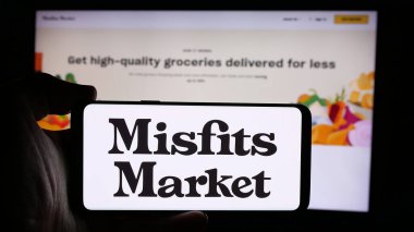 Stuttgart, Almanya - 08-26-2024: Üzerinde ABD 'li market dağıtım şirketi Misfits Market Inc.' in logosu bulunan cep telefonu sahibi kişi iş sayfasının önünde. Telefon ekranına odaklan.