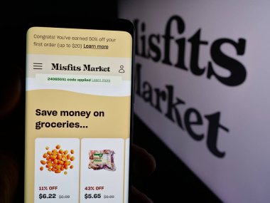 Stuttgart, Almanya - 08-26-2024: ABD 'li market dağıtım şirketi Misfits Market Inc.' in internet sayfası ile logo önünde cep telefonu tutan kişi. Telefon ekranının merkezine odaklan.