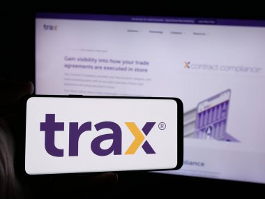Stuttgart, Almanya - 08-27-2024: Singapur 'lu Trax Technology Solutions Pte şirketinin logosuna sahip kişi. Ltd. Web sayfasının önünde. Telefon ekranına odaklan.