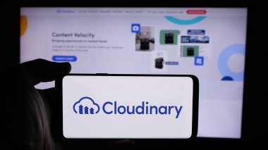 Stuttgart, Almanya - 08-27-2024: ABD 'li medya yönetim yazılım şirketi Cloudinary Ltd.' nin logosuyla cep telefonu sahibi kişi iş sayfasının önünde. Telefon ekranına odaklan.
