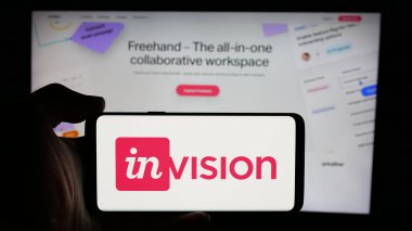Stuttgart, Almanya - 08-28-2024: ABD 'li işbirlikçi yazılım şirketi InVisionApp Inc.' in logosuyla cep telefonu tutan kişi iş sayfasının önünde. Telefon ekranına odaklan.