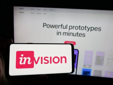 Stuttgart, Almanya - 08-28-2024: İnternet sitesi önünde ABD 'li işbirlikçi yazılım şirketi InVisionApp Inc.' in logosuna sahip akıllı telefon sahibi kişi. Telefon ekranına odaklan.