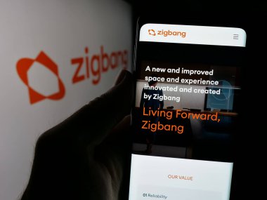 Stuttgart, Almanya - 08-28-2024: Güney Koreli emlak şirketi ZigBang 'in logo önündeki web sayfası ile akıllı telefon tutan kişi. Telefon ekranının merkezine odaklan.