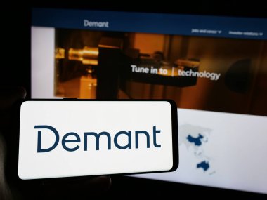Stuttgart, Almanya - 09-27-2024: Danimarkalı işitme şirketi Demant AS 'ın logosunu taşıyan cep telefonu sahibi kişi iş sayfasının önünde ekranda. Telefon ekranına odaklan.