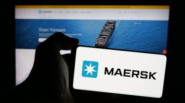 Stuttgart, Almanya - 09-27-2024: Üzerinde Danimarkalı nakliye şirketi A.P. logosu olan cep telefonu tutan kişi Moller - Maersk AS web sayfasının önünde. Telefon ekranına odaklan.