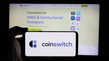 Stuttgart, Germany - 09-27-2024: Person holding mobile phone with logo of Indian crypto platform company CoinSwitch on screen in front of web page. Focus on phone display. clipart