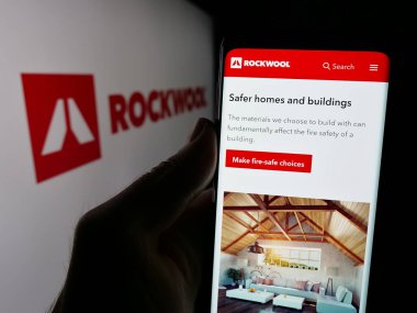 Stuttgart, Almanya - 09-29-2024: Danimarkalı mineral şirketi Rockwool AS 'nin web sayfası ile logo önünde cep telefonu tutan kişi. Telefon ekranının merkezine odaklan.