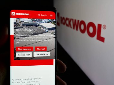 Stuttgart, Almanya - 09-29-2024: Logo önünde ekranda Danimarkalı mineral şirketi Rockwool AS 'nin web sayfası bulunan cep telefonu sahibi kişi. Telefon ekranının merkezine odaklan.