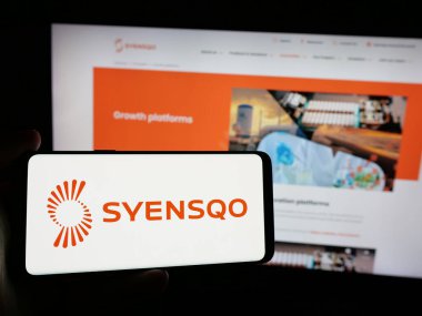 Stuttgart, Almanya - 09-29-2024: Belçikalı malzeme şirketi Syensqo SA 'nın logosunu elinde tutan kişi web sitesinin önünde ekranda. Telefon ekranına odaklan.