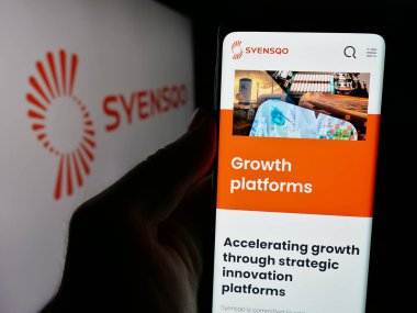 Stuttgart, Almanya - 09-29-2024: Belçikalı malzeme şirketi Syensqo SA 'nın web sayfası ile logo önünde cep telefonu tutan kişi. Telefon ekranının merkezine odaklan.