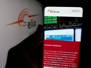 Stuttgart, Almanya - 09-29-2024: Belçika şirketi Elia Transmission Belçika SA 'nın internet sayfası ile cep telefonu tutan kişi logolu ekranda. Telefon ekranının merkezine odaklan.