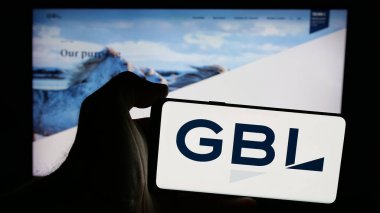Stuttgart, Almanya - 09-29-2024: Web sayfası önünde Groupe Bruxelles Lambert S.A. (GBL) şirketinin logosuna sahip cep telefonu sahibi kişi. Telefon ekranına odaklan.