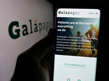 Stuttgart, Almanya - 09-29-2024: Belçikalı ilaç şirketi Galapagos NV 'nin internet sayfası ile akıllı telefonu elinde tutan kişi logolu ekranda. Telefon ekranının merkezine odaklan.