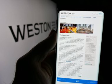 Stuttgart, Almanya - 10-01-2024: Kanadalı holding şirketi George Weston Limited 'in internet sayfası ile cep telefonu tutan kişi logolu ekranda. Telefon ekranının merkezine odaklan.