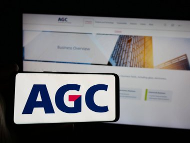 Stuttgart, Almanya - 10-01-2024: Japon cam imalat şirketi AGC Inc. 'nin logosunu elinde tutan kişi web sitesinin önünde ekranda. Telefon ekranına odaklan.
