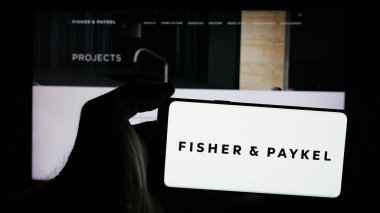 Stuttgart, Almanya - 10-01-2024: Fisher Paykel Appliances Holding 'in logosunun bulunduğu cep telefonu sahibi kişi web sayfasının önünde ekranda görülüyor. Telefon ekranına odaklan.