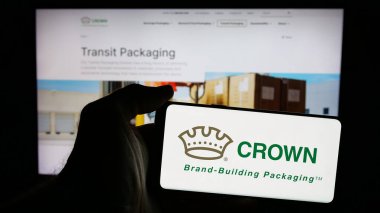 Stuttgart, Almanya - 10-01-2024: ABD 'li ambalaj şirketi Crown Holding Inc.' in logosunu elinde tutan kişi web sitesinin önünde ekranda. Telefon ekranına odaklan.