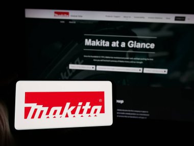 Stuttgart, Almanya - 10-01-2024: Japon elektrikli aletler şirketi Makita Corporation 'ın logosunu elinde tutan kişi web sitesinin önünde ekranda. Telefon ekranına odaklan.