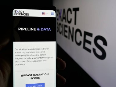 Stuttgart, Almanya - 10-02-2024: ABD 'li biyoteknoloji şirketi Exact Sciences Corporation' ın web sayfası ile akıllı telefonu elinde tutan kişi logolu ekranda. Telefon ekranının merkezine odaklan.