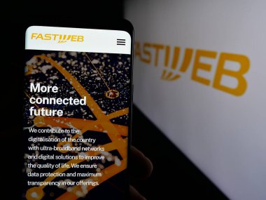 Stuttgart, Almanya - 10-04-2024: Telekomünikasyon şirketi FastWeb S.P.A. 'nın web sayfası olan cep telefonu logonun önünde ekranda. Telefon ekranının merkezine odaklan.