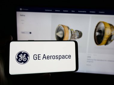 Stuttgart, Almanya - 10-04-2024: ABD 'li GE Aerospace (General Electric) şirketinin logosuna sahip akıllı telefon sahibi kişi web sitesinin önünde ekranda. Telefon ekranına odaklan.