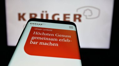 Stuttgart, Almanya - 10-04-2024: Alman gıda şirketi Krueger GmbH Co. KG 'nin web sitesi ile cep telefonu iş logosu önünde ekranda. Telefon ekranının sol üst kısmına odaklan.