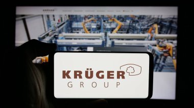 Stuttgart, Almanya - 10-04-2024: Alman gıda şirketi Krueger GmbH Co. KG 'nin logosuyla cep telefonu sahibi kişi iş sayfasının önünde ekranda. Telefon ekranına odaklan.