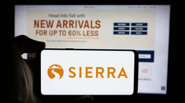 Stuttgart, Almanya - 10-04-2024: Perakende şirketi Sierra Trading Post 'un logosuyla cep telefonu sahibi kişi iş sayfasının önünde ekranda. Telefon ekranına odaklan.