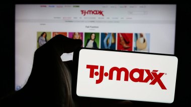 Stuttgart, Almanya - 10-04-2024: İnternet sitesi önünde ekranda ABD 'li indirimli mağaza şirketi TJ Maxx' in logosunu taşıyan kişi. Telefon ekranına odaklan.