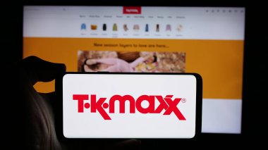 Stuttgart, Almanya - 10-04-2024: Perakende satış şirketi TK Maxx 'in logosuyla cep telefonu sahibi kişi iş sayfasının önünde ekranda. Telefon ekranına odaklan.