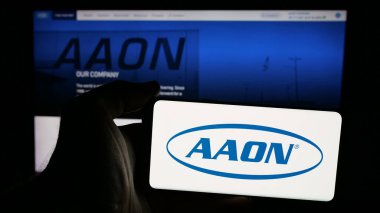Stuttgart, Almanya - 10-07-2024: Web sayfasının önünde ekranda Amerikan HVAC ekipman şirketi AAON Inc. 'nin logosunun bulunduğu cep telefonu sahibi kişi. Telefon ekranına odaklan.