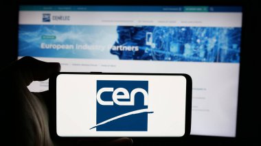 Stuttgart, Almanya - 10-07-2024: İnternet sitesi önünde Avrupa Standartlaştırma Komitesi (CEN) logosu olan akıllı telefon sahibi kişi. Telefon ekranına odaklan.