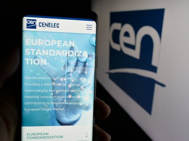 Stuttgart, Almanya - 10-07-2024: Avrupa Standartlaştırma Komitesi 'nin (CEN) web sitesinin logolu cep telefonu sahibi kişi. Telefon ekranının merkezine odaklan.