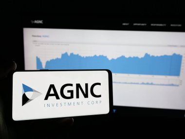 Stuttgart, Almanya - 10-08-2024: Amerikan AGNC Yatırım Şirketi logosu olan cep telefonu sahibi kişi iş sayfasının önünde ekranda. Telefon ekranına odaklan.