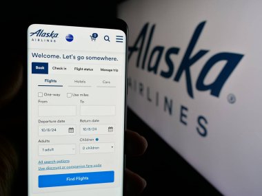 Stuttgart, Almanya - 10-08-2024: ABD 'li havayolu şirketi Alaska Air Group Inc.' in web sayfası ile cep telefonu tutan kişi logonun önünde ekranda. Telefon ekranının merkezine odaklan.