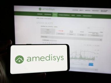Stuttgart, Almanya - 10-08-2024: Amerikan sağlık şirketi Amedisys Inc. 'in logosunun bulunduğu cep telefonu web sayfası önünde ekranda. Telefon ekranına odaklan.