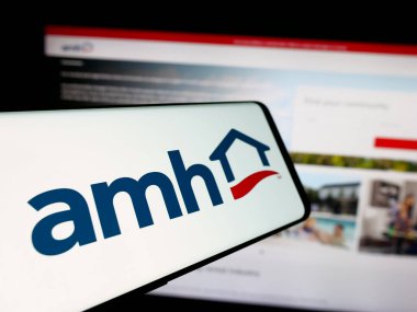 Stuttgart, Almanya - 10-08-2024: Amerikan Homes 4 Rent LP (AMH) şirketinin logosuna sahip cep telefonu iş sitesinin önünde ekranda. Telefon ekranının merkez sağına odaklan.