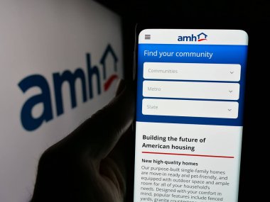 Stuttgart, Almanya - 10-08-2024: ABD 'li Homes 4 Rent LP (AMH) şirketinin web sayfası logonun önünde duran kişi. Telefon ekranının merkezine odaklan.